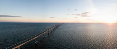 Aerial Panoramic view of Confederation Bridge to Prince Edward Island during a vibrant sunny sunrise. Taken in Cape Jourimain National Wildlife Area, New Brunswick, Canada. clipart
