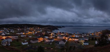 Panoramik bir karanlık bulutlu gün batımı sırasında Atlantik Okyanusu kıyısında küçük bir kasaba. Karga baş, Kuzey Twillingate Island, Newfoundland ve Labrador, Kanada içinde alınan.