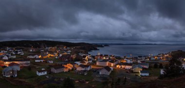 Panoramic view of a small town on the Atlantic Ocean Coast during a dark cloudy sunset. Taken in Crow Head, North Twillingate Island, Newfoundland and Labrador, Canada. clipart
