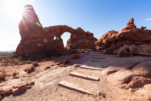 Scenic path leading to an Arch rock formation during a vibrant sunny day. Taken in Arches National Park, located near Moab, Utah, United States.