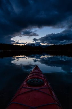 Huzurlu ve sakin Buzul gölü içinde canlı bir bulutlu gün batımı sırasında kayak. Maligne gölde, Jasper National Park, Alberta, Kanada alınan.