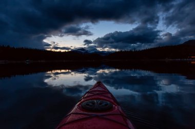 Huzurlu ve sakin Buzul gölü içinde canlı bir bulutlu gün batımı sırasında kayak. Maligne gölde, Jasper National Park, Alberta, Kanada alınan.