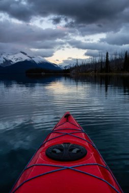Huzurlu ve sakin Buzul gölü içinde canlı bir bulutlu gün batımı sırasında kayak. Maligne gölde, Jasper National Park, Alberta, Kanada alınan.