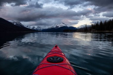 Huzurlu ve sakin Buzul gölü içinde canlı bir bulutlu gün batımı sırasında kayak. Maligne gölde, Jasper National Park, Alberta, Kanada alınan.