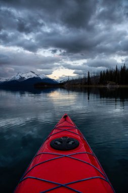 Huzurlu ve sakin Buzul gölü içinde canlı bir bulutlu gün batımı sırasında kayak. Maligne gölde, Jasper National Park, Alberta, Kanada alınan.