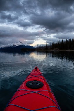 Huzurlu ve sakin Buzul gölü içinde canlı bir bulutlu gün batımı sırasında kayak. Maligne gölde, Jasper National Park, Alberta, Kanada alınan.