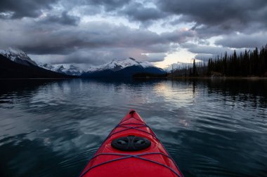 Huzurlu ve sakin Buzul gölü içinde canlı bir bulutlu gün batımı sırasında kayak. Maligne gölde, Jasper National Park, Alberta, Kanada alınan.