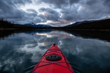 Huzurlu ve sakin Buzul gölü içinde canlı bir bulutlu gün batımı sırasında kayak. Maligne gölde, Jasper National Park, Alberta, Kanada alınan.
