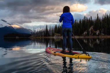 Kız yatılı raket huzurlu ve sakin buzul Göl canlı bir bulutlu gün batımı sırasında. Maligne gölde, Jasper National Park, Alberta, Kanada alınan.