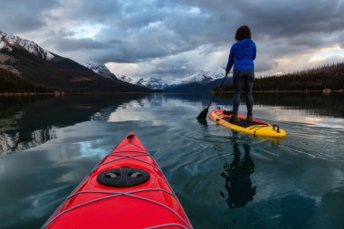 Huzurlu ve sakin Buzul gölü içinde canlı bir bulutlu gün batımı sırasında kayak. Maligne gölde, Jasper National Park, Alberta, Kanada alınan.