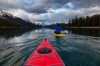 Huzurlu ve sakin Buzul gölü içinde canlı bir bulutlu gün batımı sırasında kayak. Maligne gölde, Jasper National Park, Alberta, Kanada alınan.