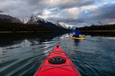 Huzurlu ve sakin Buzul gölü içinde canlı bir bulutlu gün batımı sırasında kayak. Maligne gölde, Jasper National Park, Alberta, Kanada alınan.
