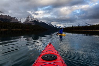 Huzurlu ve sakin Buzul gölü içinde canlı bir bulutlu gün batımı sırasında kayak. Maligne gölde, Jasper National Park, Alberta, Kanada alınan.