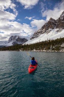 Bir bulutlu sabah sırasında Kanada Rocky Dağları ile çevrili bir buzul Gölü'kayak maceracı kız. Alınan yay Gölü, Banff, İngiltere.