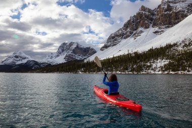 Bir bulutlu sabah sırasında Kanada Rocky Dağları ile çevrili bir buzul Gölü'kayak maceracı kız. Alınan yay Gölü, Banff, İngiltere.