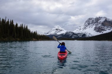 Bir bulutlu sabah sırasında Kanada Rocky Dağları ile çevrili bir buzul Gölü'kayak maceracı kız. Alınan yay Gölü, Banff, İngiltere.