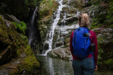 Maceracı kadın uzun yürüyüşe çıkan kimse bir şelale güzel bir manzarasına sisli bir gün zarfında keyif alıyor. MT benden, North Vancouver, British Columbia, Kanada alınan.