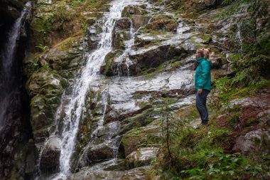 Maceracı kadın uzun yürüyüşe çıkan kimse bir şelale güzel bir manzarasına sisli bir gün zarfında keyif alıyor. MT benden, North Vancouver, British Columbia, Kanada alınan.