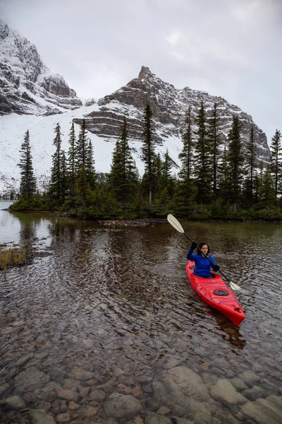 Bir bulutlu sabah sırasında Kanada Rocky Dağları ile çevrili bir buzul Gölü'kayak maceracı kız. Alınan yay Gölü, Banff, İngiltere.