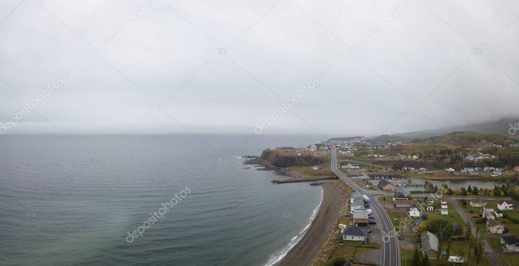 Aerial panoramic view of a small town on the Atlantic Ocean Coast during a cloudy day. Taken in Grande-Valle, Qubec, Canada.