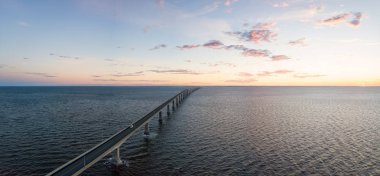 Aerial Panoramic view of Confederation Bridge to Prince Edward Island during a vibrant sunny sunrise. Taken in Cape Jourimain National Wildlife Area, New Brunswick, Canada. clipart