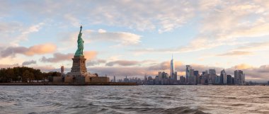 Özgürlük Anıtı ve Manhattan kent merkezinin panoramik manzaralı canlı bulutlu gün doğumu sırasında arka planda. Jersey City, New Jersey, Amerika Birleşik Devletleri'nde çekilen.