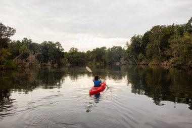 Bir nehir üzerinde bulutlu bir gece boyunca kayak maceracı kız. Orlando, Florida, Amerika Birleşik Devletleri batısında bulunan Chassahowitzka Nehri'nde alınan.