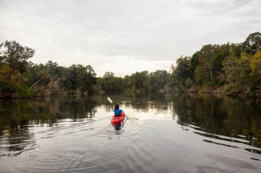 Bir nehir üzerinde bulutlu bir gece boyunca kayak maceracı kız. Orlando, Florida, Amerika Birleşik Devletleri batısında bulunan Chassahowitzka Nehri'nde alınan.
