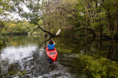 Maceracı kız bir nehir kanosu ağaçlarıyla kaplı. Orlando, Florida, Amerika Birleşik Devletleri batısında bulunan Chassahowitzka Nehri'nde alınan.
