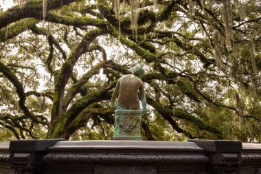 Old rusty statue in a park surrounded by beautiful trees during a foggy morning. Taken in City Park, New Orleans, Louisiana, United States.