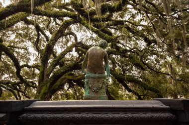 Old rusty statue in a park surrounded by beautiful trees during a foggy morning. Taken in City Park, New Orleans, Louisiana, United States.