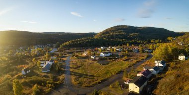 Aerial view of a small town on a rocky Atlantic Ocean Coast during a bright sunny sunrise. Taken in Little Bay, Newfoundland, Canada.