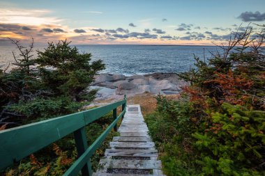 Ahşap merdiven güzel kayalık Atlantik Okyanusu kıyısında canlı bir gün batımı sırasında aşağı gidiyor. İnek kafası, Newfoundland, Canada alınan.