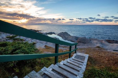 Ahşap merdiven güzel kayalık Atlantik Okyanusu kıyısında canlı bir gün batımı sırasında aşağı gidiyor. İnek kafası, Newfoundland, Canada alınan.