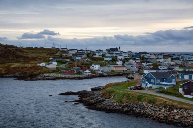 Bir bulutlu gün batımı sırasında kayalık Atlantik Okyanusu kıyısında küçük bir kasaba evlerinde. Kanal-Port aux Bask, alınan Newfoundland, Canada.