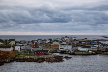 Bir bulutlu gün batımı sırasında kayalık Atlantik Okyanusu kıyısında küçük bir kasaba evlerinde. Kanal-Port aux Bask, alınan Newfoundland, Canada.
