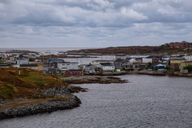 Bir bulutlu gün batımı sırasında kayalık Atlantik Okyanusu kıyısında küçük bir kasaba evlerinde. Kanal-Port aux Bask, alınan Newfoundland, Canada.