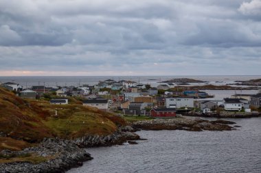 Bir bulutlu gün batımı sırasında kayalık Atlantik Okyanusu kıyısında küçük bir kasaba evlerinde. Kanal-Port aux Bask, alınan Newfoundland, Canada.