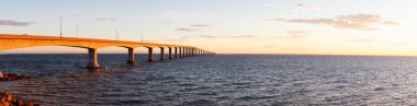 Panoramic view of Confederation Bridge to Prince Edward Island during a vibrant sunny sunrise. Taken in Cape Jourimain National Wildlife Area, New Brunswick, Canada. clipart