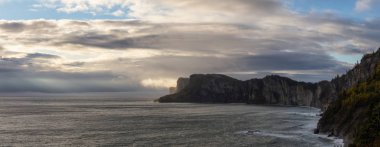 Striking panoramic landscape of a rocky coastline during a cloudy sunrise. Taken in Forillon National Park, near Gaspe, Quebec, Canada clipart