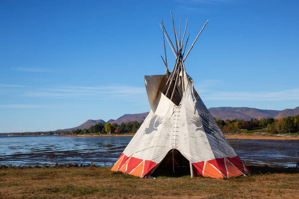 Gesgapegiag, Quebec, Canada - October 5, 2018: North American Indians Teepee near the Atlantic Ocean shore during a vibrant sunny day.