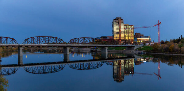 Bridge over the river in a downtown city during a vibrant sunrise. Saskatoon, Saskatchewan, Canada.