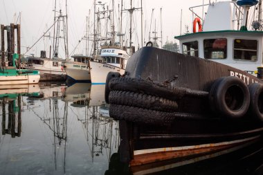 Ucluelet, Vancouver Island, BC, Canada - August 21, 2018: Fishing boats at a marina during a smoky and vibrant morning sunrise. clipart