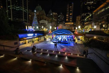 Downtown Vancouver, British Columbia, Canada - December 31, 2018: Crowd of people are ice skating in Robson Square during New Year's Eve. clipart