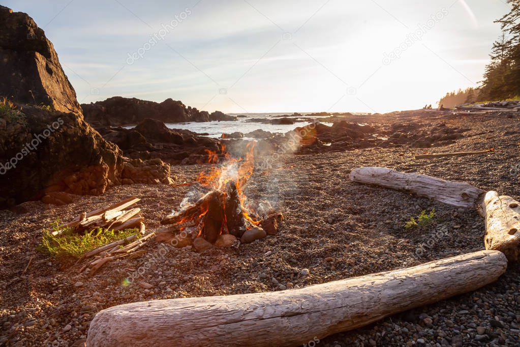 Camp fire on the beach during a vibrant summer sunset. Taken in Northern Vancouver Island Ocean Coast, BC, Canada.