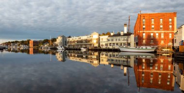 Mystic, Stonington, Connecticut, United States - October 26, 2018: Panoramic view of old historic homes by the Mystic River during a vibrant sunrise. clipart