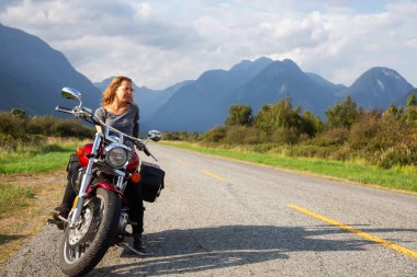 Kadın Kanada dağlarla çevrili doğal bir yol üzerinde bir motosiklet Binme. Pitt Meadows, büyük Vancouver, Bc, Kanada alınan.