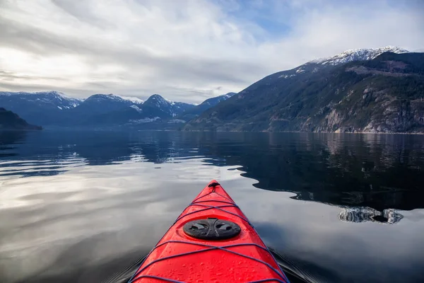 Sea kayaking in peaceful water during a cloudy winter day. Taken in Squamish, North of Vancouver, BC, Canada.