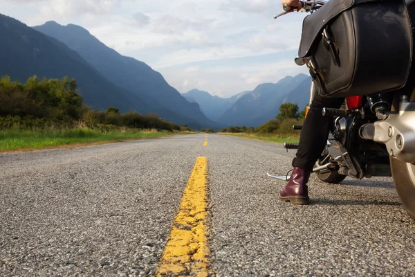 Woman riding a motorcycle on a scenic road surrounded by Canadian Mountains. Taken in Pitt Meadows, Greater Vancouver, BC, Canada.