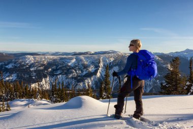 Beyaz maceracı kız bir dağın tepesinde bir canlı kış günbatımı sırasında snowshoeing. Umut, British Columbia, Kanada yakınındaki Zoa tepe üstüne alınan.
